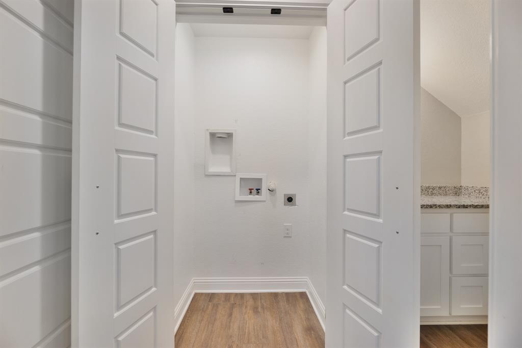 1713 Bronco Road Granbury, TX 76049 - Photo 10 of 23 Dedicated laundry area with wood-finish flooring, white baseboards, and panel-style bifold doors