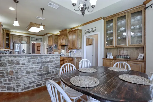 a kitchen with stainless steel appliances granite countertop a sink a stove a dining table and chairs