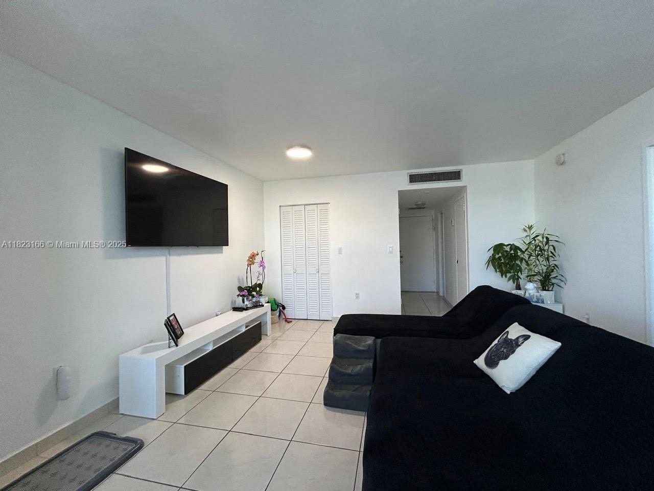 2899 Collins Avenue, Unit 1717 Miami Beach, FL 33140 - Photo 16 of 32 a living room with furniture and a flat screen tv