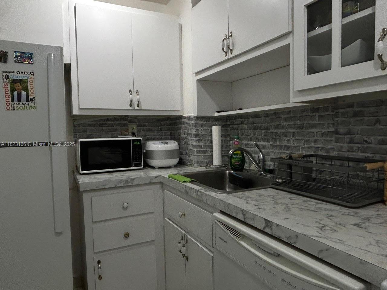 2899 Collins Avenue, Unit 1717 Miami Beach, FL 33140 - Photo 23 of 32 a kitchen with a sink and cabinets