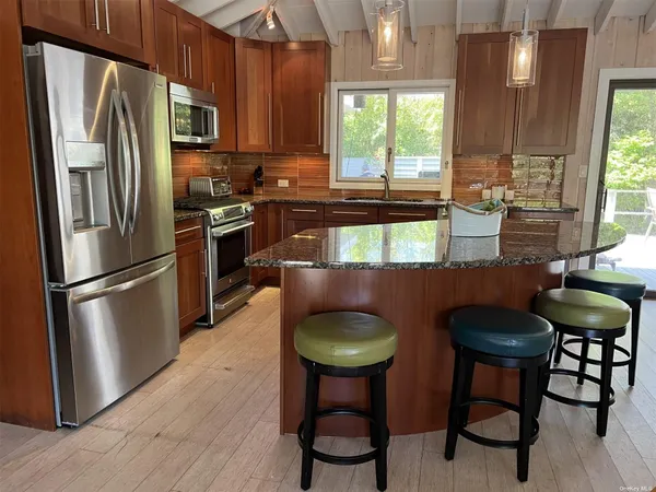 a kitchen with stainless steel appliances a table chairs refrigerator and window