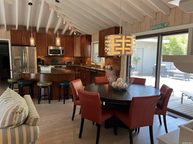 a dining room with furniture a kitchen a chandelier and a wooden floor