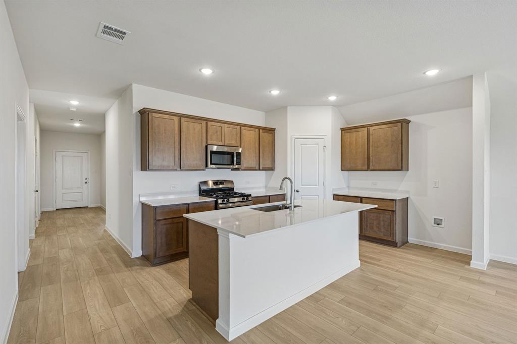 3820 Prairie Chapel Road Royse City, TX 75189 - Photo 3 of 18 a large kitchen with stainless steel appliances granite countertop a stove top oven a sink dishwasher and a refrigerator with wooden floor