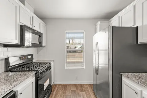 a kitchen with granite countertop cabinets stainless steel appliances a sink and wooden floor