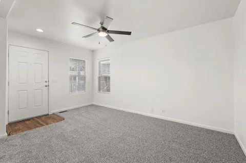 an empty room with windows and fan