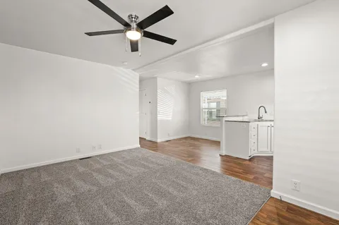 a view of empty room with wooden floor and ceiling fan