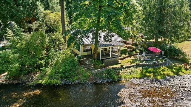 a front view of a house with a yard and a large tree