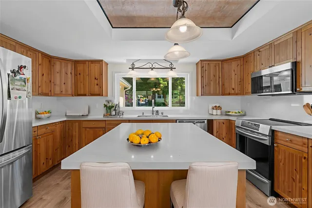 a kitchen with stainless steel appliances granite countertop a sink a stove a refrigerator cabinets and a window