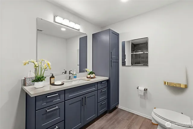 a bathroom with a double vanity sink and mirror with toilet