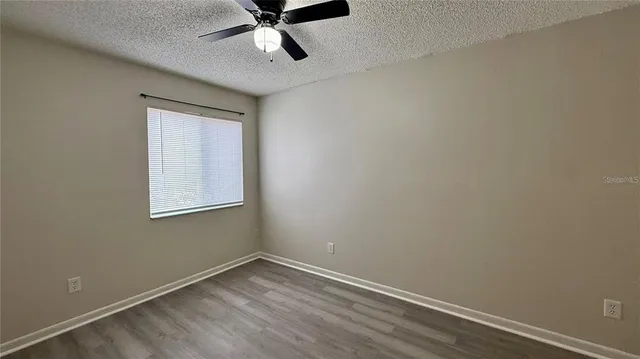 an empty room with a window and a fan