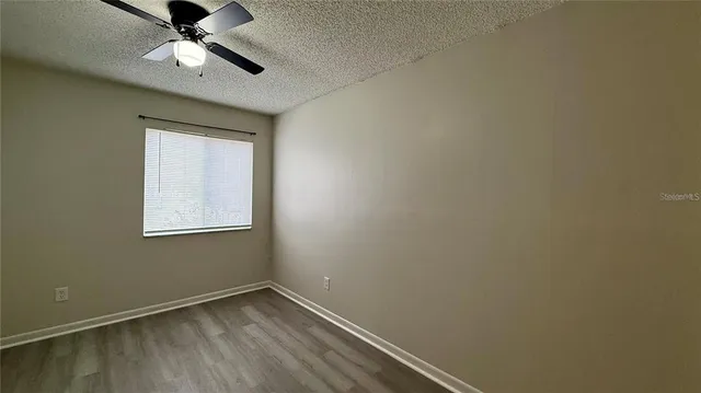 an empty room with a window and ceiling fan