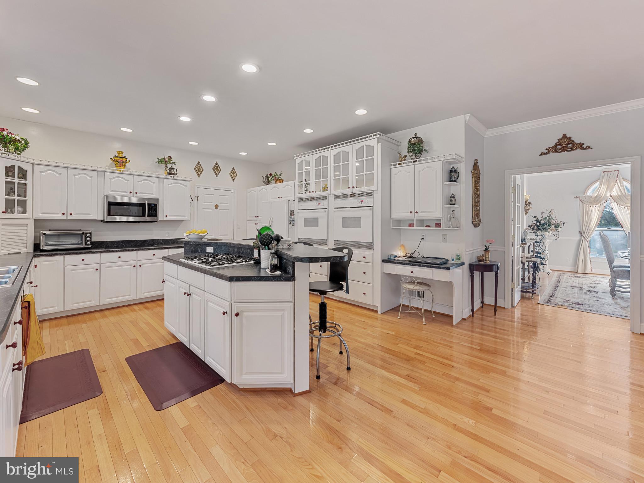 10900 Sunset Hills Road Reston, VA 20190 - Photo 29 of 62 a kitchen with stainless steel appliances granite countertop a stove top oven a sink dishwasher and white cabinets with wooden floor