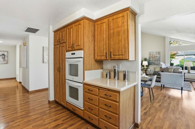 a kitchen with stainless steel appliances granite countertop a refrigerator a stove top oven a dining table and chairs with wooden floor