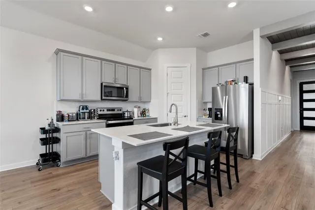 a kitchen with a table a refrigerator a cabinets and stools