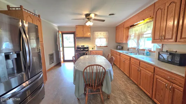 a large kitchen with stainless steel appliances granite countertop a refrigerator a sink dishwasher a dining table and chairs with wooden floor