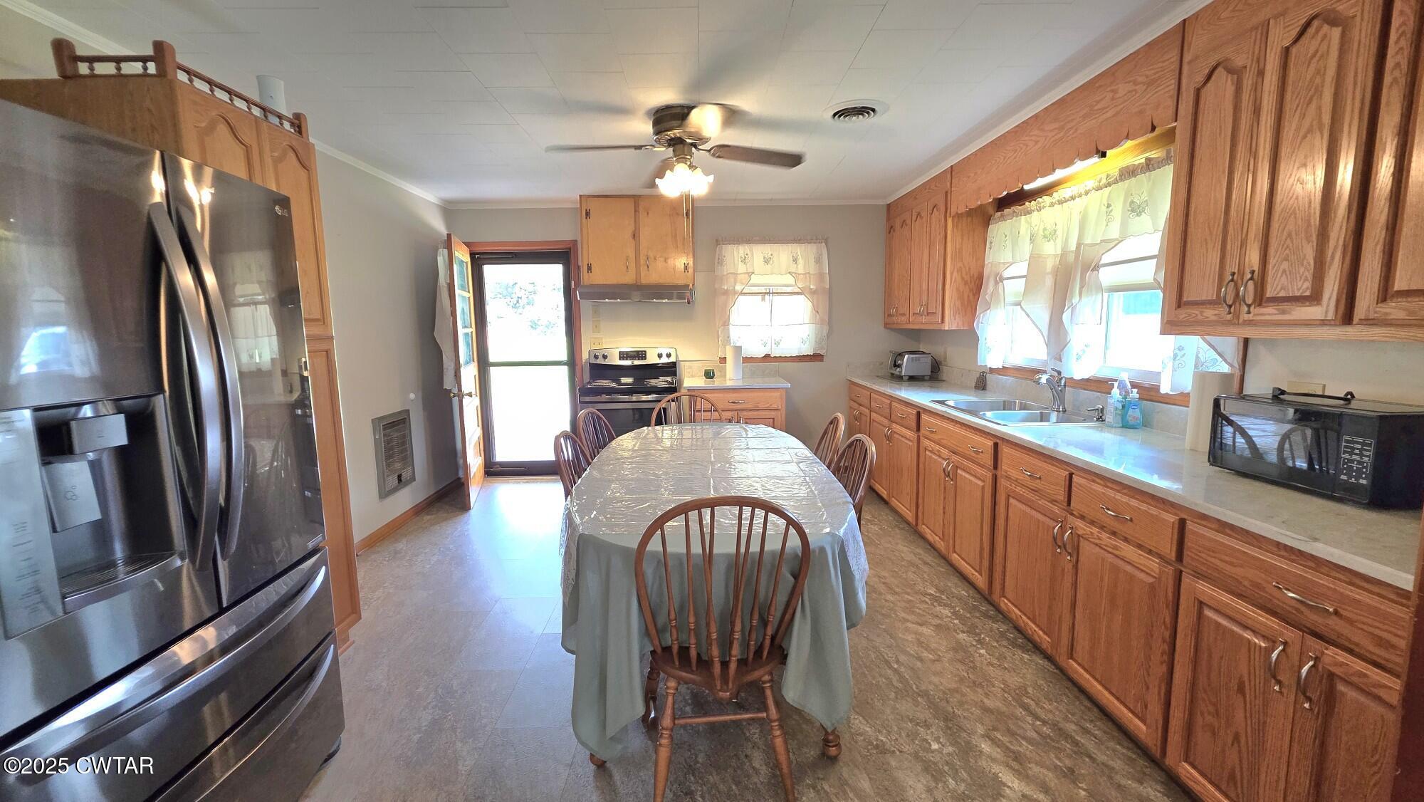 811 Gibson Road Trenton, TN 38382 - Photo 5 of 23 a large kitchen with stainless steel appliances granite countertop a refrigerator a sink dishwasher a dining table and chairs with wooden floor