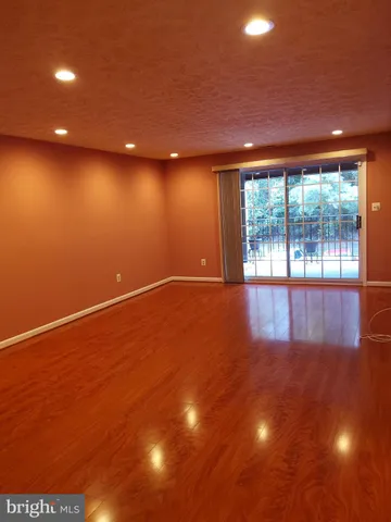 a view of an empty room with wooden floor and windows