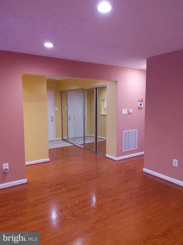 a view of an empty room with wooden floor and a carpet