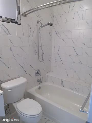 a white toilet sitting next to a bath tub and a shower