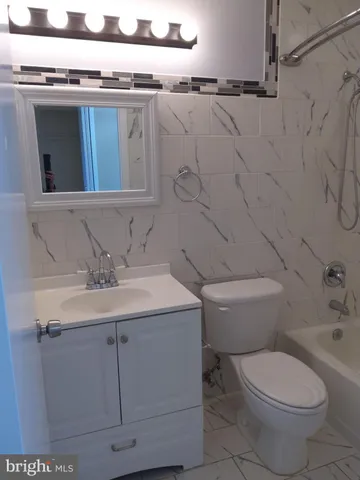 a bathroom with a granite countertop toilet sink and mirror