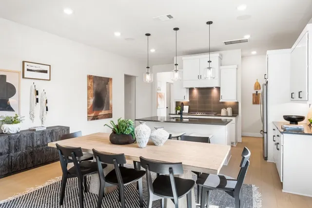 a kitchen with stainless steel appliances kitchen island granite countertop a dining table chairs and white cabinets