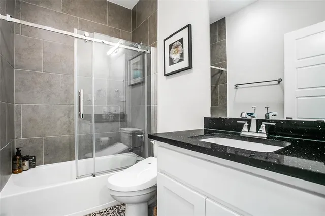 a bathroom with a granite countertop sink a toilet and bathtub