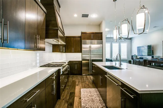 a kitchen with stainless steel appliances granite countertop a sink a stove and a wooden floors