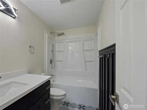 a bathroom with a granite countertop sink a toilet and shower