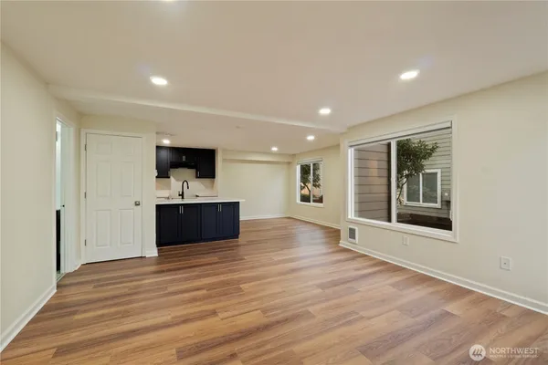 a view of an empty room with a kitchen and a window