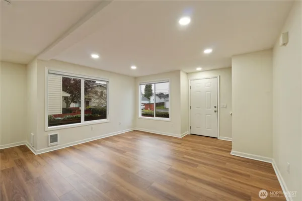 a view of a big room with wooden floor and windows