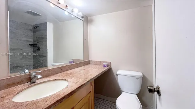 a bathroom with a granite countertop toilet sink and mirror