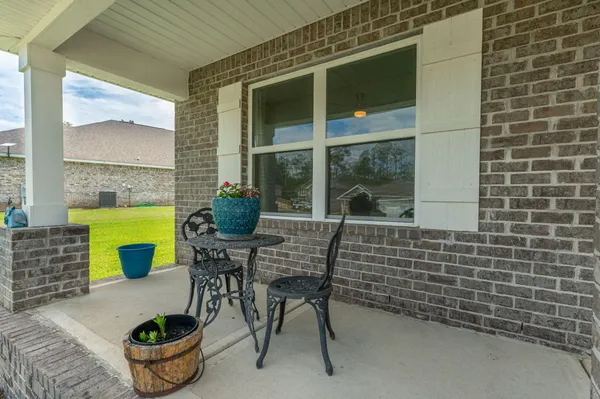 a balcony with table and chairs potted plants