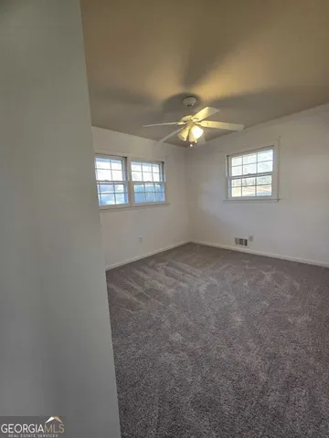 en empty room with windows and chandelier fan