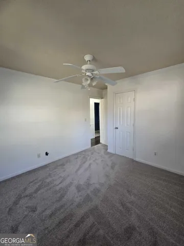 an empty room with a chandelier fan and windows