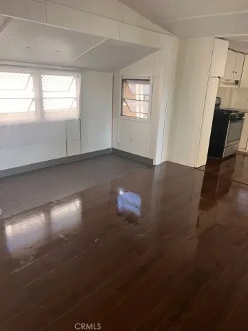 an empty room with wooden floor and windows in it