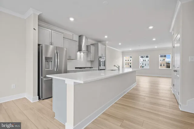 a view of a kitchen with kitchen island a sink wooden floor and stainless steel appliances