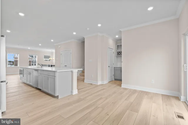 a view of a kitchen with kitchen island stainless steel appliances cabinets and wooden floor