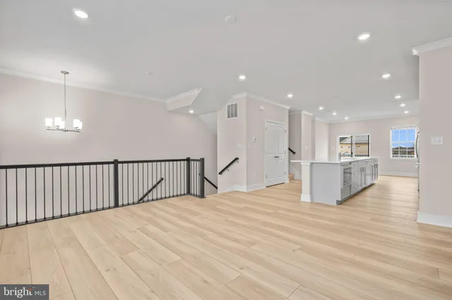 a view of an empty room with wooden floor and kitchen