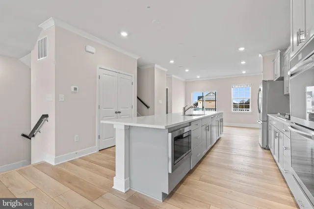 a large white kitchen with kitchen island a sink a counter top space stainless steel appliances and a center island