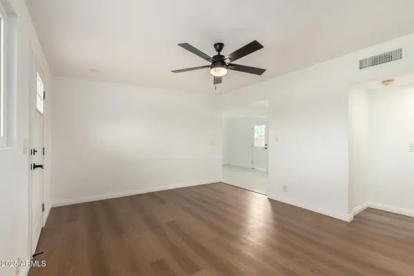 an empty room with wooden floor ceiling fan and windows