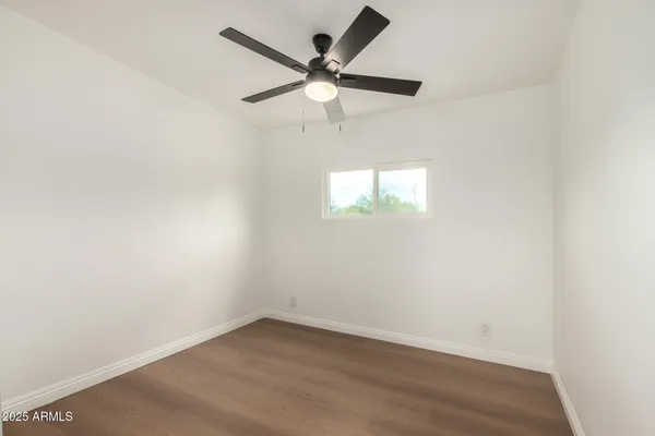 an empty room with a window and a ceiling fan