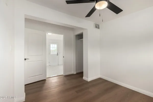 an empty room with wooden floor cabinet and windows