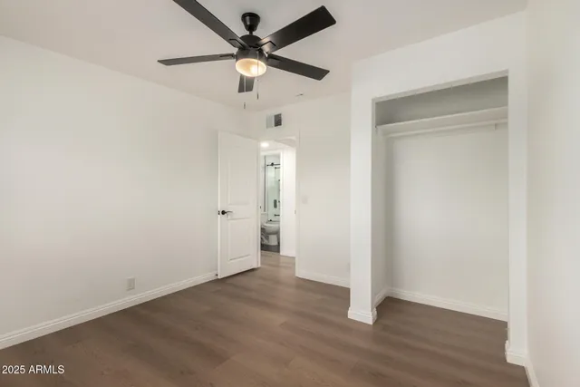 an empty room with wooden floor and a ceiling fan