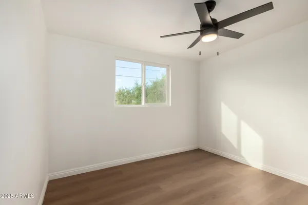 an empty room with a window and a fan