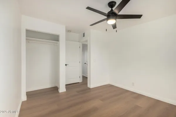 an empty room with wooden floor and ceiling fan
