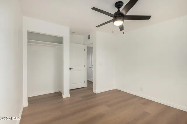 an empty room with wooden floor and ceiling fan
