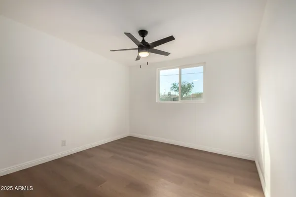 an empty room with a window and a ceiling fan