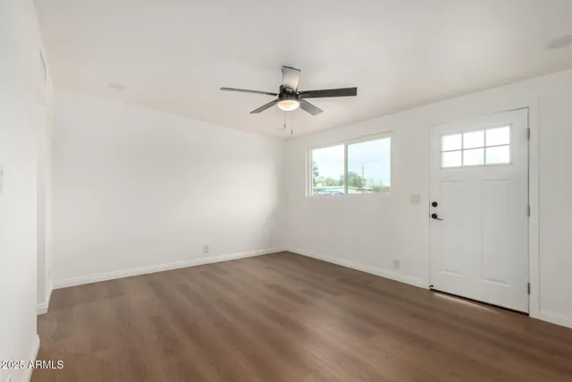 an empty room with wooden floor ceiling fan and windows