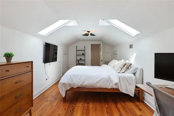 a bedroom with a bed and a flat tv screen on dresser