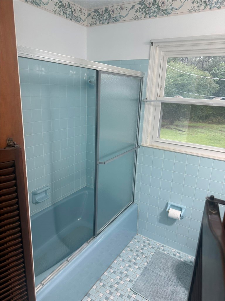 4027 Belhaven Road Belton, SC 29627 - Photo 13 of 24 A well-maintained bathroom with a blue tiled tub and shower enclosure offers a refreshing aesthetic.